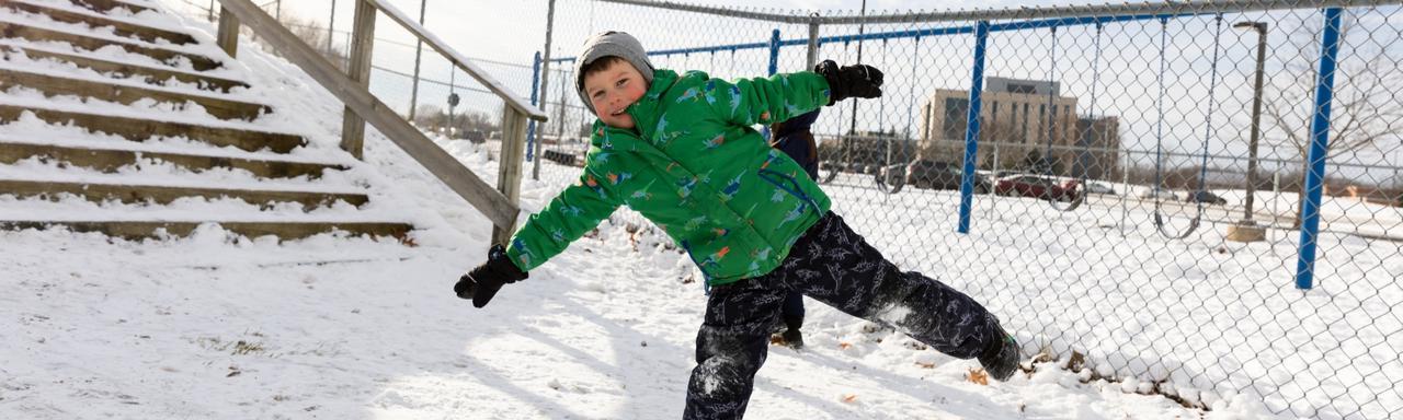 Kid standing on one leg with arms out in the snow